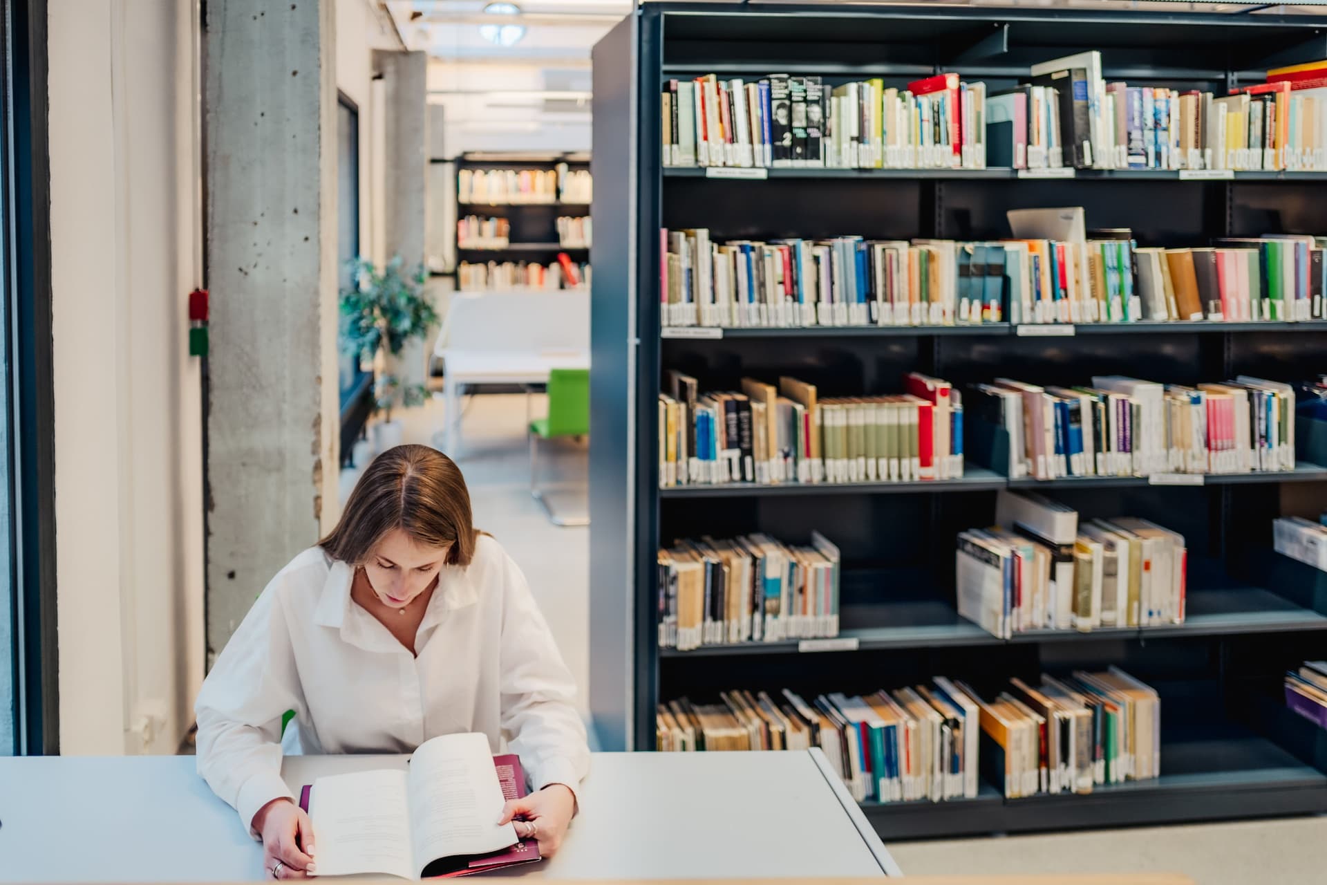 Dame som leser bok i et bibliotek