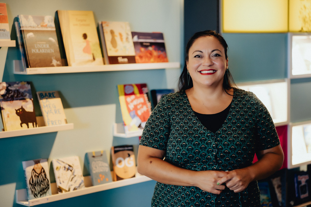 Veronica Salinas stående foran en vegg med utstilte bøker. 